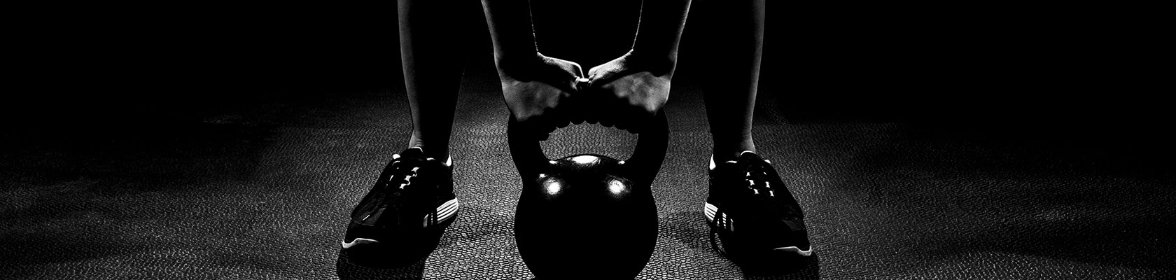 a black and white image of someone holding the handle of a kettle bell on the ground